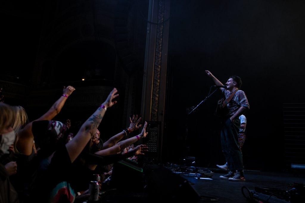 Fans raising their hands to reach out to Milky Chance as he points to the balcony.