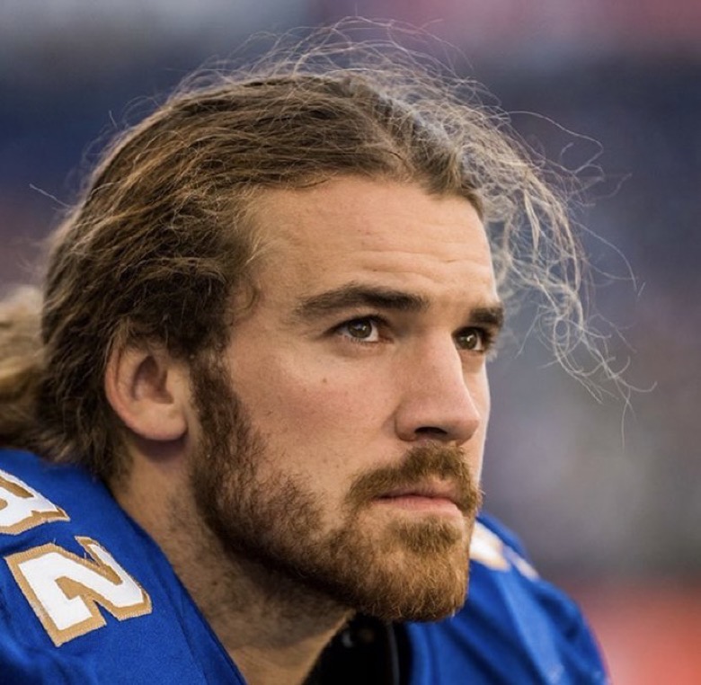 A close-up shot of a football player, wearing a blue and gold jersey, looking in the distance.