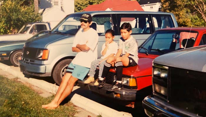 Mauricio, Ivonne, and Mauricio jr sitting on a red 1982 Volkswagen Jetta parked watching a soccer game (not in frame)