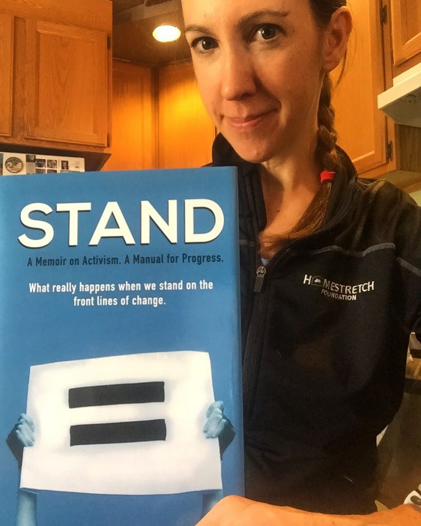 A woman holds a physical copy of her memoir, STAND. 