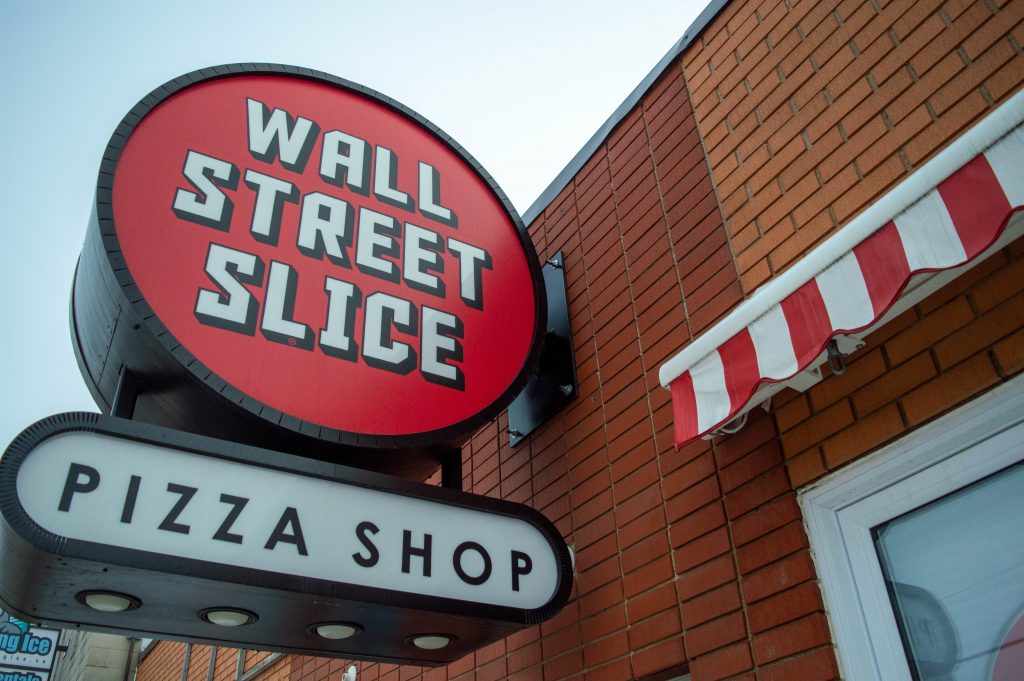 The clean Wall Street Slice sign with a brick background