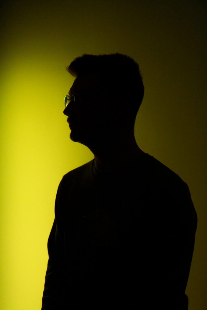 A man is silhouetted on a yellow background.