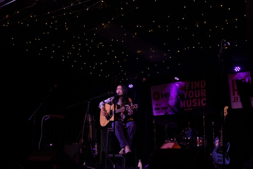 Hera Nalam plays her guitar on stage