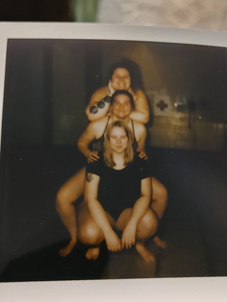 Three women pose for a polaroid photo 