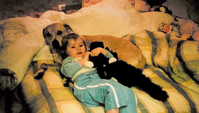 Two-year-old Kaylen Arnal Cuddling her dog Lexie on a bed.